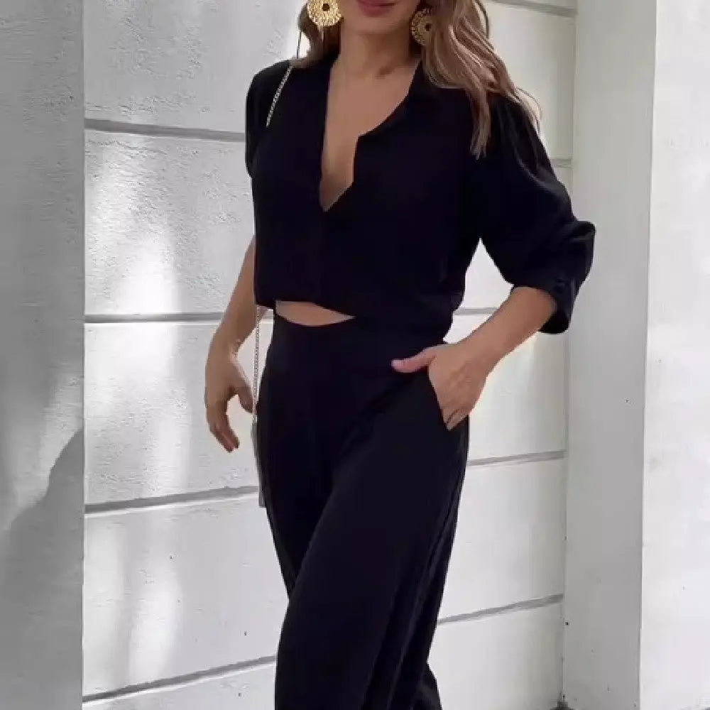 Elegant black women's suit with short top and wide-leg pants.