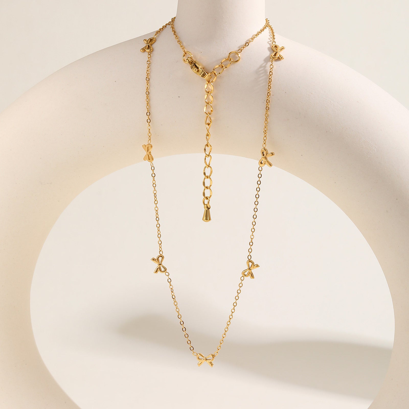 European and American style stainless steel necklace featuring a flat cross pendant and a bow design, showcasing elegant jewelry craftsmanship.