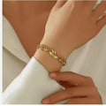 Stainless steel oval leaf bracelet with engraved hollow design and embedded birthstone, showcasing detailed craftsmanship.
