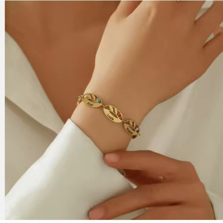 Stainless steel oval leaf bracelet with engraved hollow design and embedded birthstone, showcasing detailed craftsmanship.