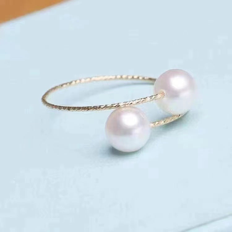 Elegant open ring featuring two freshwater pearls on a sleek band, showcasing timeless jewelry craftsmanship.