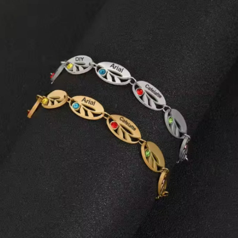 Stainless steel hollow oval leaf bracelet engraved with a birthstone, showcasing detailed leaf design and a colorful gemstone.
