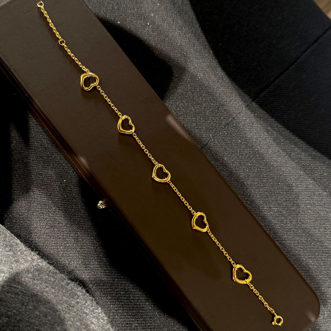 Gold plated open heart station chain bracelet with delicate design, featuring small heart charms along a fine chain.