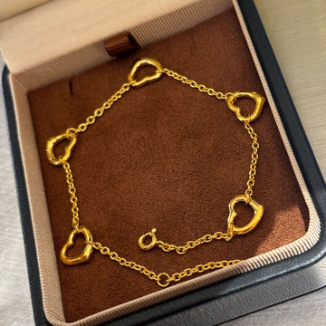 Gold plated open heart station chain bracelet with delicate design, featuring small heart charms along a fine chain.