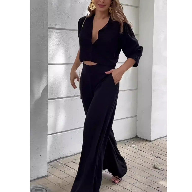 Elegant black women's suit with short top and wide-leg pants.